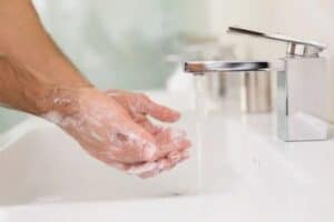 man washing hands after applying topical combo hair loss spray